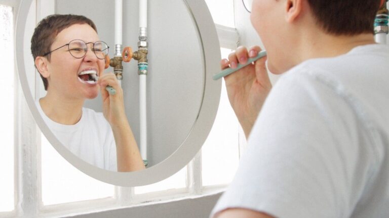 Person brushing teeth in front of mirror at home